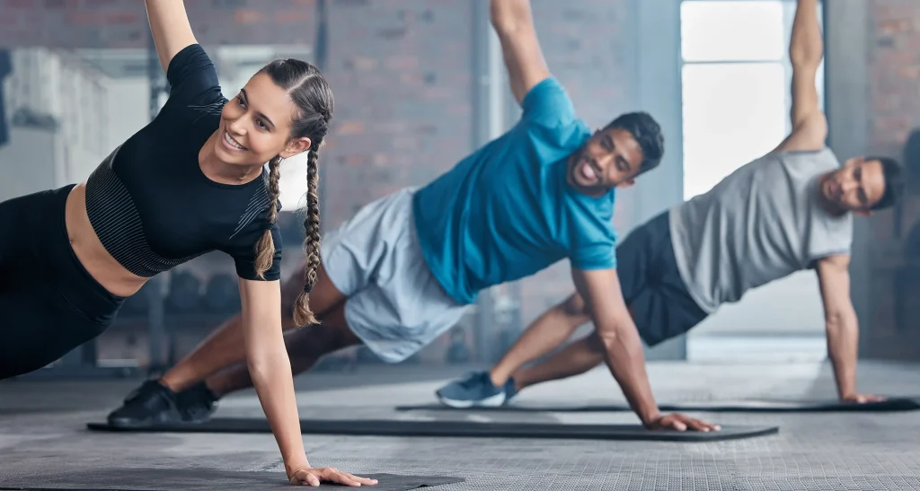 team and stretching arms for workout, exercise or training together with smile at the gym